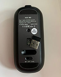a black wireless mouse from the bottom showing power switch button and USB receiver slot
